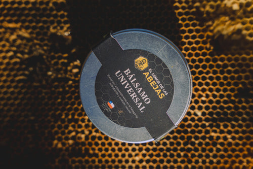 Lata de Bálsamo Universal de El Señor de las Abejas sobre un marco de panal